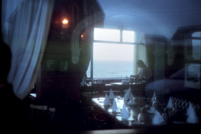Un restaurant vu par une fenêtre à Waterville, une serveuse prépare les tables, il y a des reflets bleutés