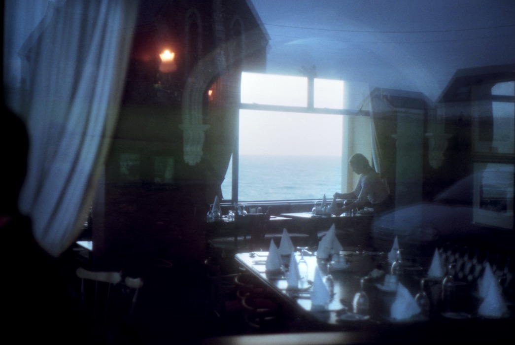 Un restaurant vu par une fenêtre à Waterville, une serveuse prépare les tables, il y a des reflets bleutés